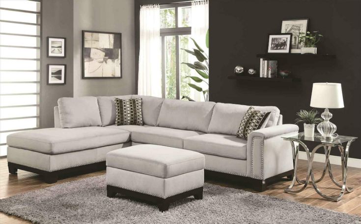 a living room with a sectional couch and ottoman