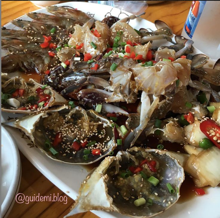 a white plate topped with oysters covered in sauce and garnished with green onions