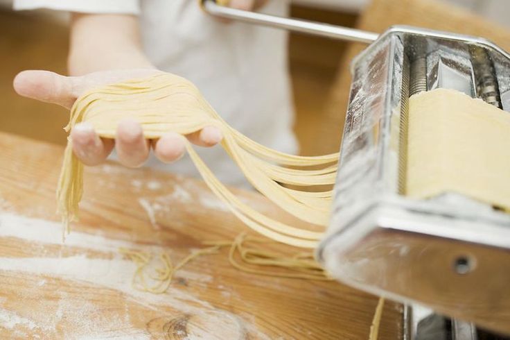 a person is pulling pasta out of a toaster with one hand and holding the other