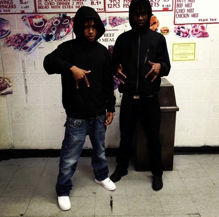 two young men standing next to each other in front of a wall with posters on it