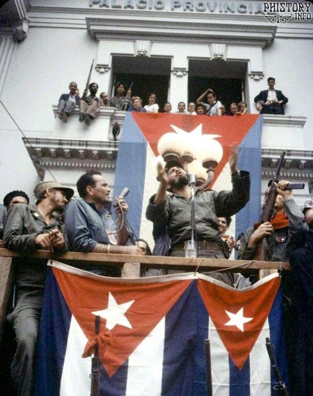 a group of people standing on top of a balcony next to each other holding flags