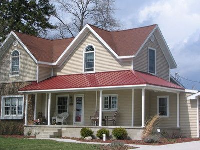 a two story house with a red metal roof and white trim on the front porch