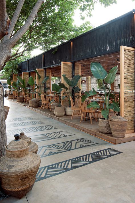 an outdoor restaurant with tables and chairs next to a tree