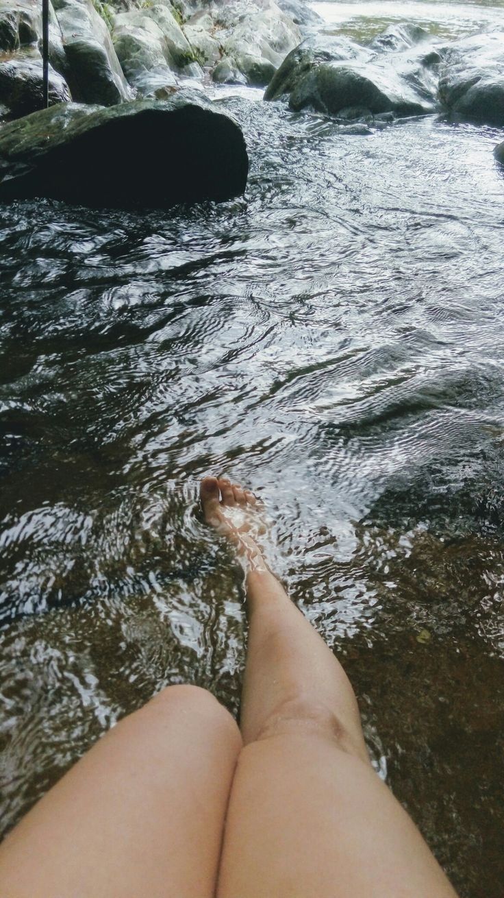 a woman's legs are in the water near rocks