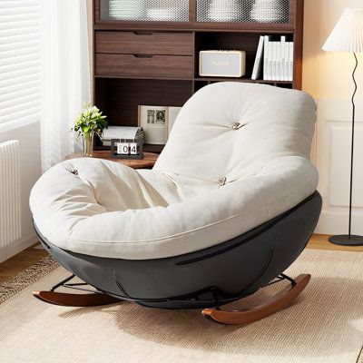 a chair that is sitting in front of a book shelf with a lamp on it