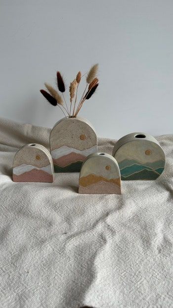 three small wooden vases sitting on top of a bed