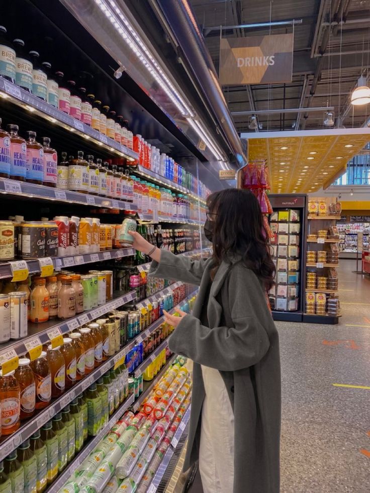 a woman is looking at the shelves in a grocery store while she shops for food