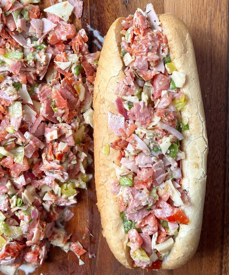 two hot dogs with toppings sitting on top of a wooden table