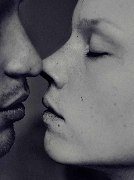 a man and woman kissing each other with their noses close to one another in black and white