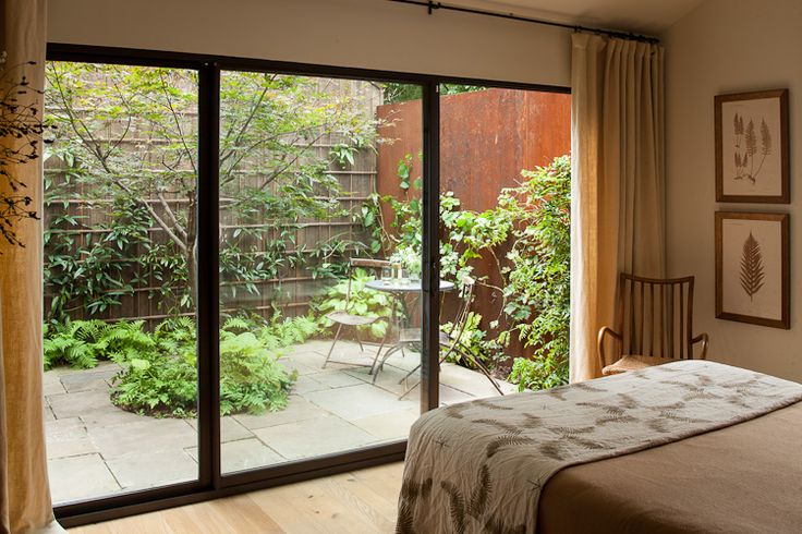 a bedroom with sliding glass doors leading to a patio and garden outside the door is shown