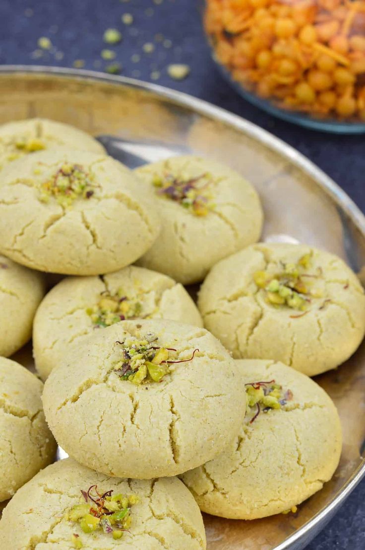 some cookies are on a silver plate next to other food items