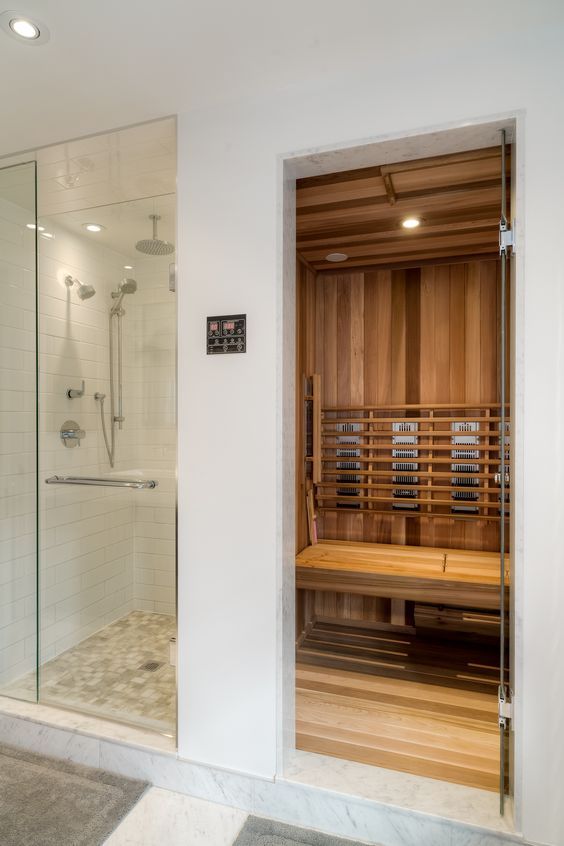 a bathroom with a walk in shower next to a wooden saunach and tiled floor