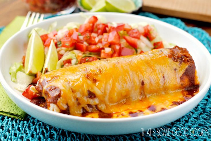 a white bowl filled with taco salad and an enchilada wrapped in tortilla