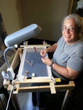 a woman sitting in front of a table with an easel on top of it