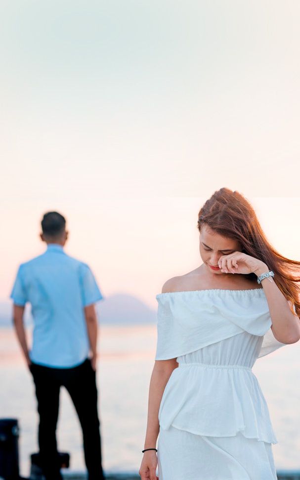 a man standing next to a woman near the ocean