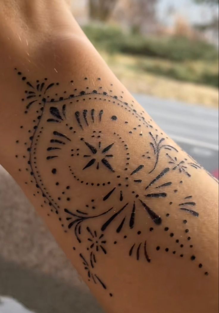 a close up of a person's arm with an intricate tattoo design on it