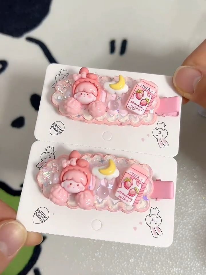 two small pink hair clips with animals and stars on them, one being held in the other's hand