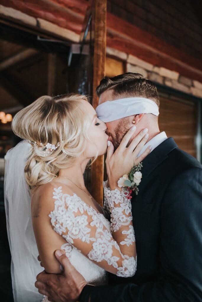 a bride and groom kissing each other in front of a wooden structure at the end of their wedding day