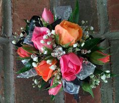 an orange and pink flower bouquet sitting on top of a brick wall