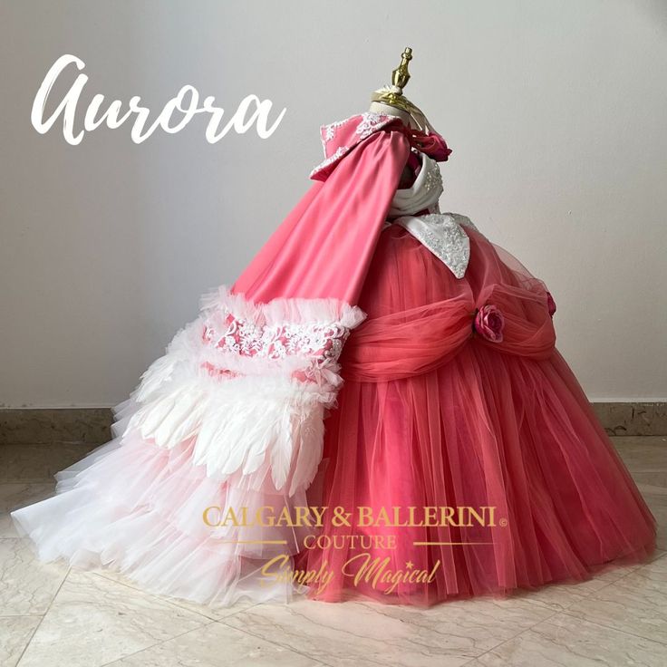 a pink and white dress on display with the name aurora written in gold above it