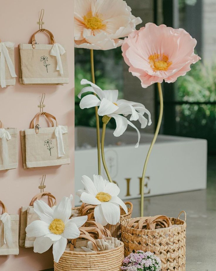 three baskets with flowers in them are next to a wall hanging on the pink wall