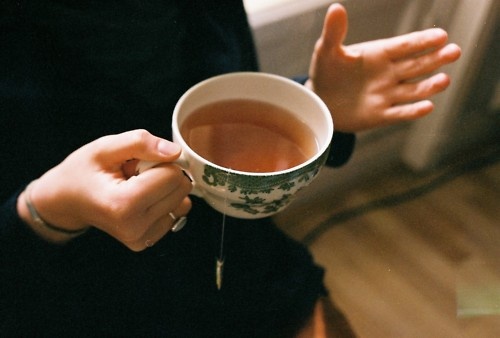 a woman holding a cup of tea in her hands