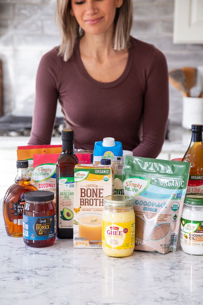 a woman sitting at a kitchen counter surrounded by ingredients for making an apple cider