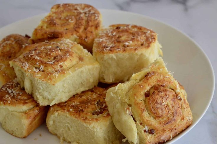 a white plate topped with rolls on top of a marble countertop covered in powdered sugar