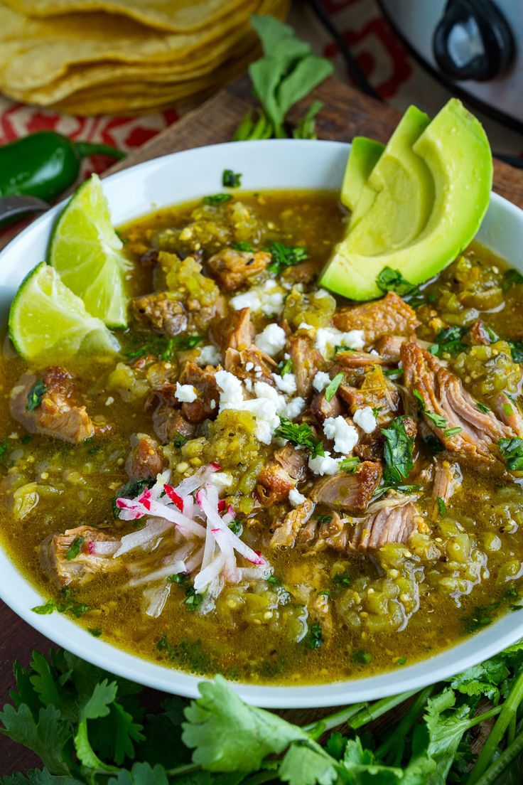 a white bowl filled with chicken and tortilla soup next to cilantro