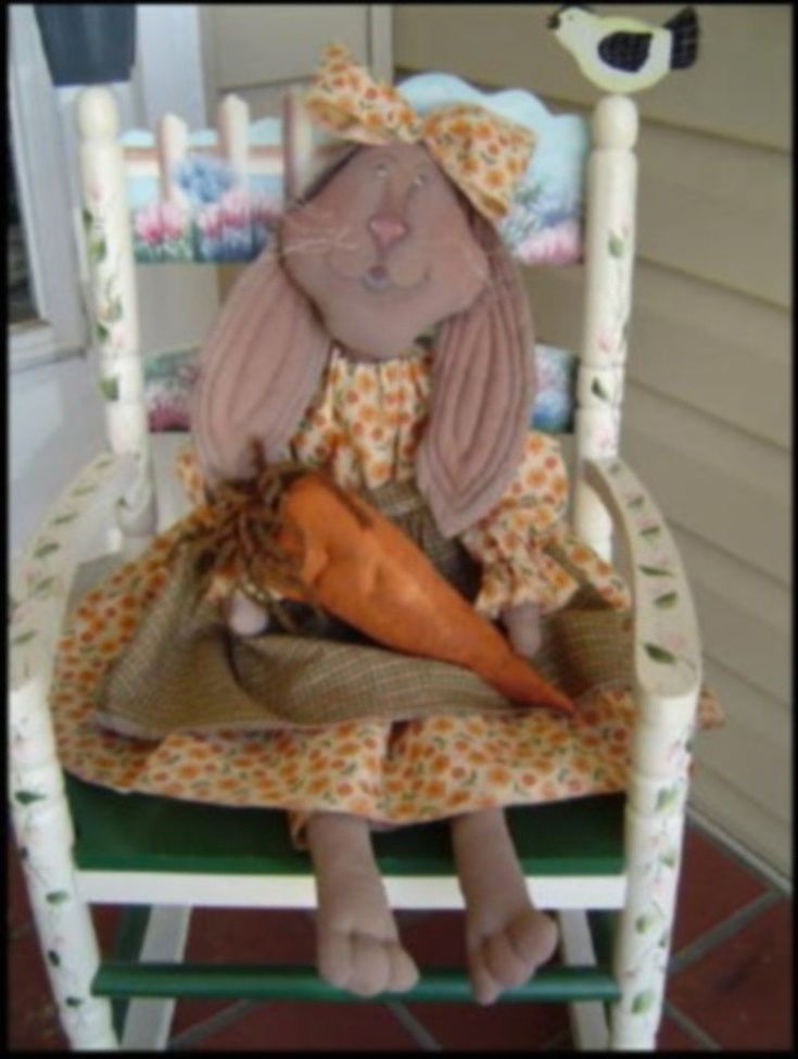 a doll sitting in a rocking chair with a carrot on it's back legs