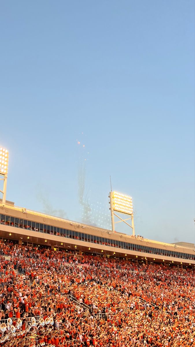 an empty stadium filled with people watching the game on a sunny day in orange and white