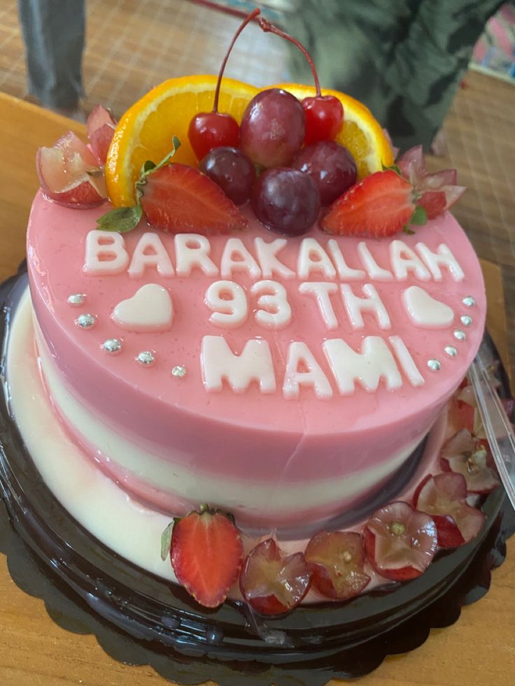 a birthday cake with fruit and writing on it