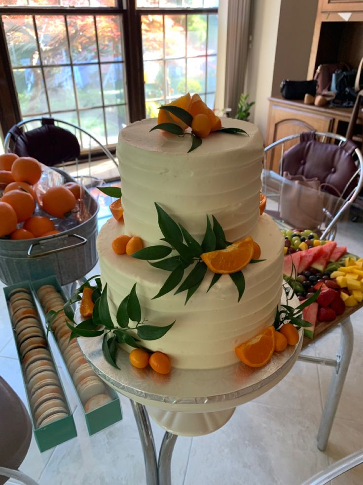 a three tiered white cake with oranges on it