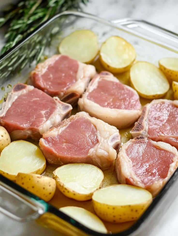 raw meat and potatoes in a glass casserole dish