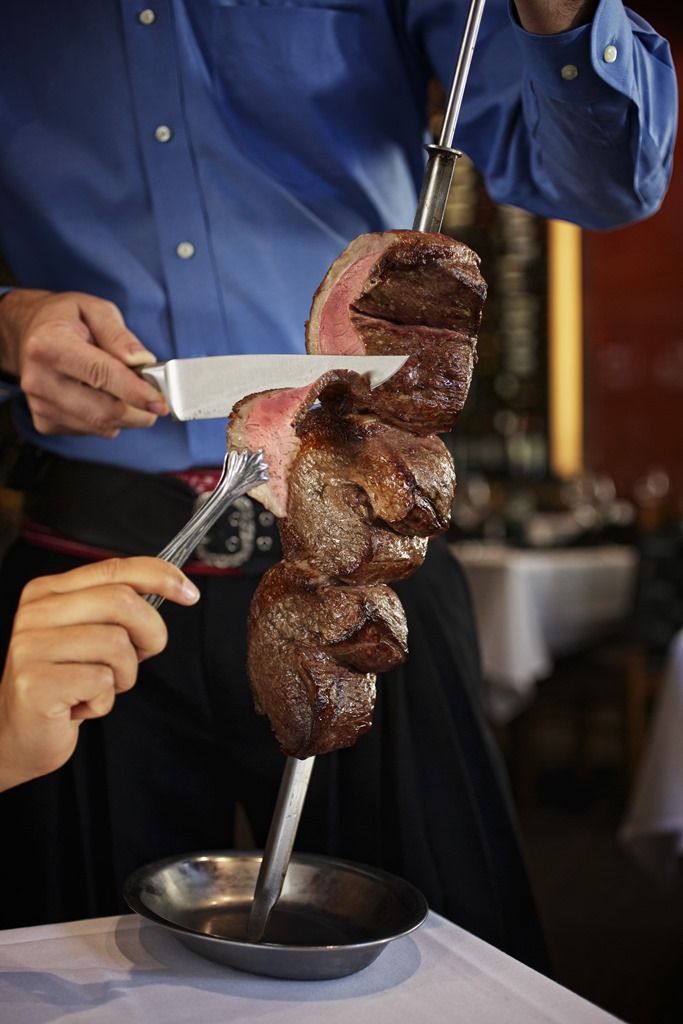 a man is cutting meat on a skewer