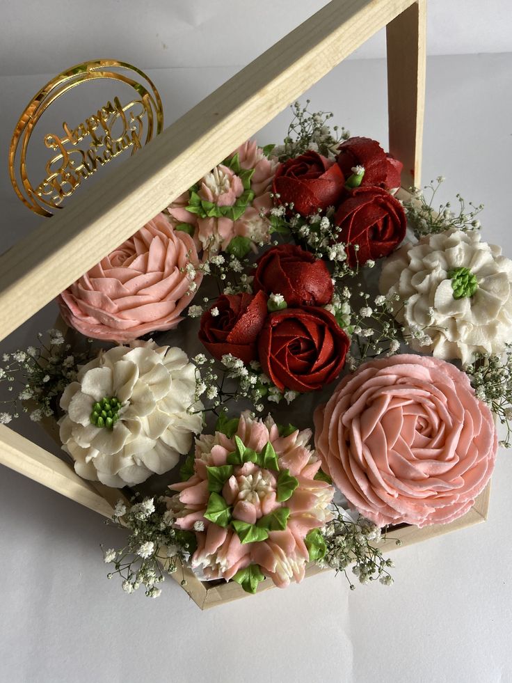 a bouquet of pink and red flowers in a wooden box