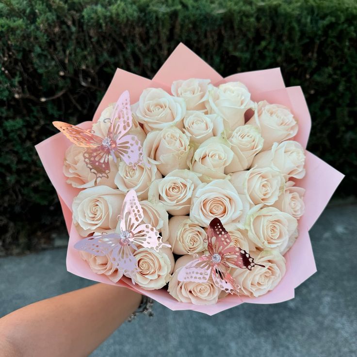 someone holding a bouquet of white roses and butterflies