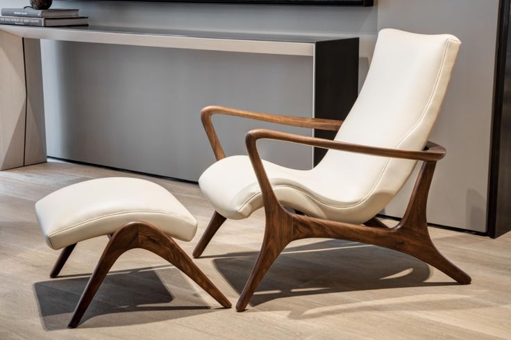 a white chair and ottoman in front of a tv on a wall with a wooden frame