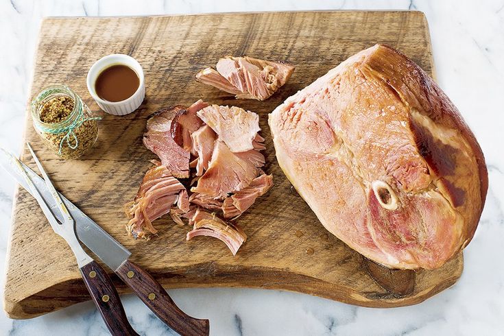 ham is cut up on a cutting board and ready to be served with sauces