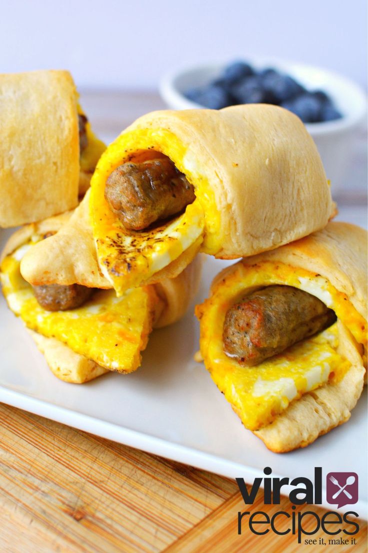 sausage and egg breakfast rolls on a white plate with blueberries in the background, ready to be eaten