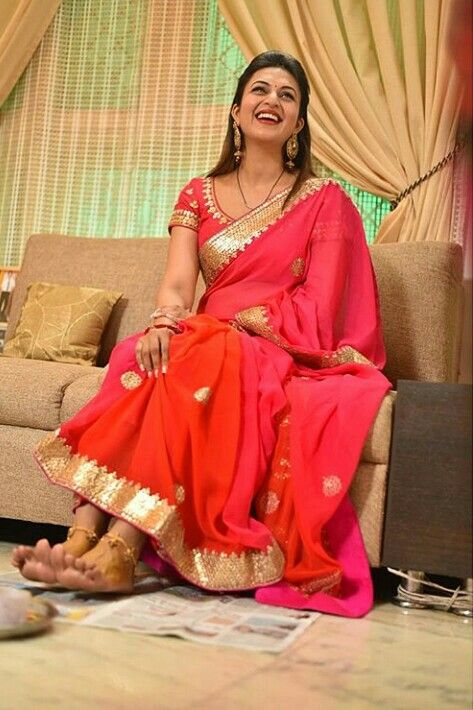 a woman in a red sari sitting on a couch