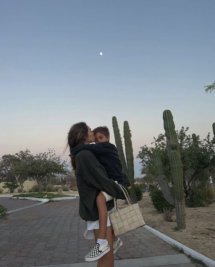 a man and woman kissing in front of cacti with the moon behind them