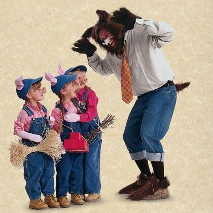 a man standing next to two small children wearing costumes and holding an animal over his head