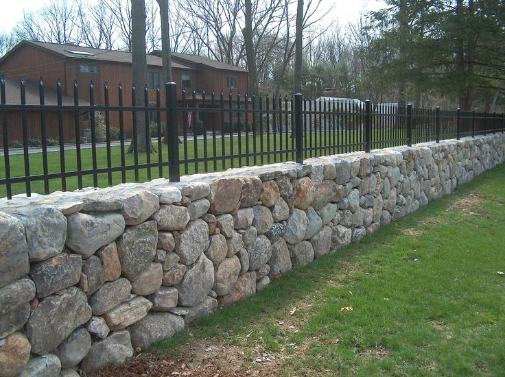 a stone wall with black iron fence surrounding it