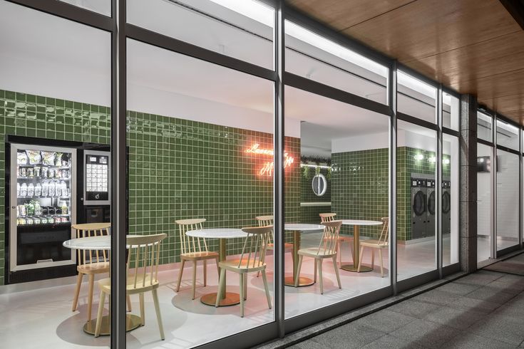 an empty restaurant with green tiles on the walls and tables in front of glass doors