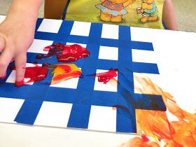 a child is painting with red paint on a blue and white checkered table cloth