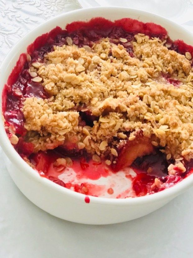 a close up of a bowl of food with berries and crumbled toppings