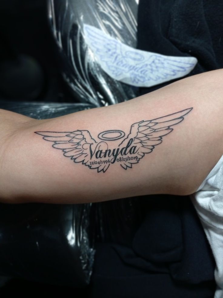 a person with a tattoo on their arm that reads vanda and has wings around it