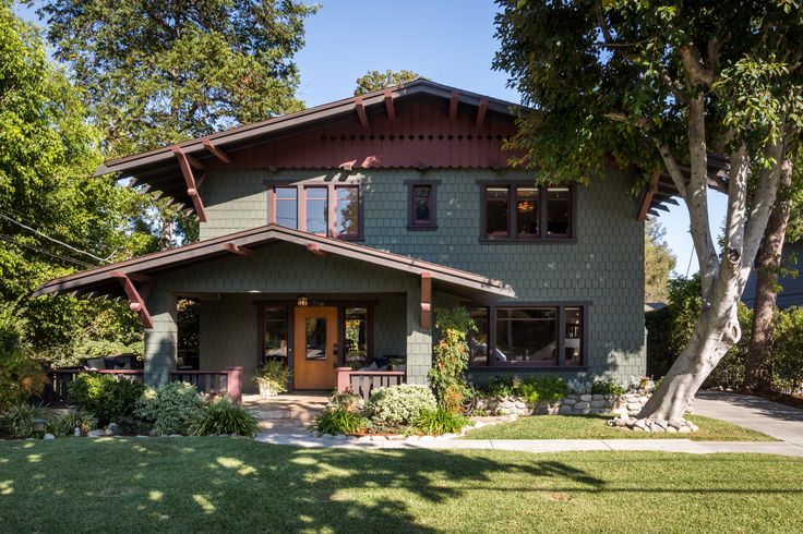 a green house with trees in front of it and grass on the side walk to the door