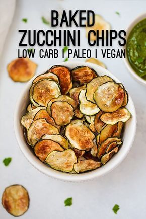 baked zucchini chips in a white bowl with pesto sauce on the side